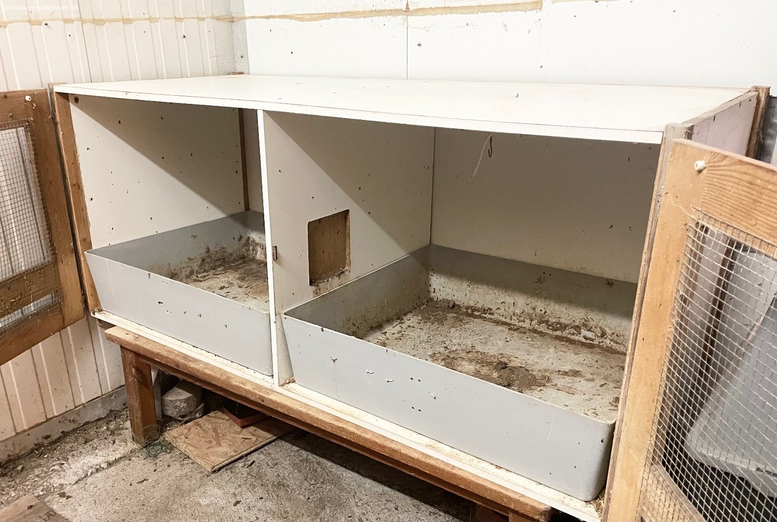 Landi UFA Kaninchen Doppelstall Grossrassen. Grosszügiger UFA Doppelstall für Grossrassen, mit hohen Schubladen und verschliessbarem Durchgang. Alles weissen Flächen, also quasi der komplette Stall, innen und aussen, ist abwaschbar. Er stand immer indoor, entsprechend ist die Holzqualität sehr gut. Wurde vor einigen Jahren grob geleert und steht seitdem leer. Entsprechend braucht er ein Abstauben und kurze Reinigung, was durch die abwaschbaren Flächen problemlos klappt. Einige massive Doppel-Futternäpfe können bei Interesse mitgenommen werden. Der Stall steht auf einem Kieferntisch, welcher bei Bedarf des Abholers auch dabei ist. Länge 165cm, Tiefe 76cm, Höhe 72cm